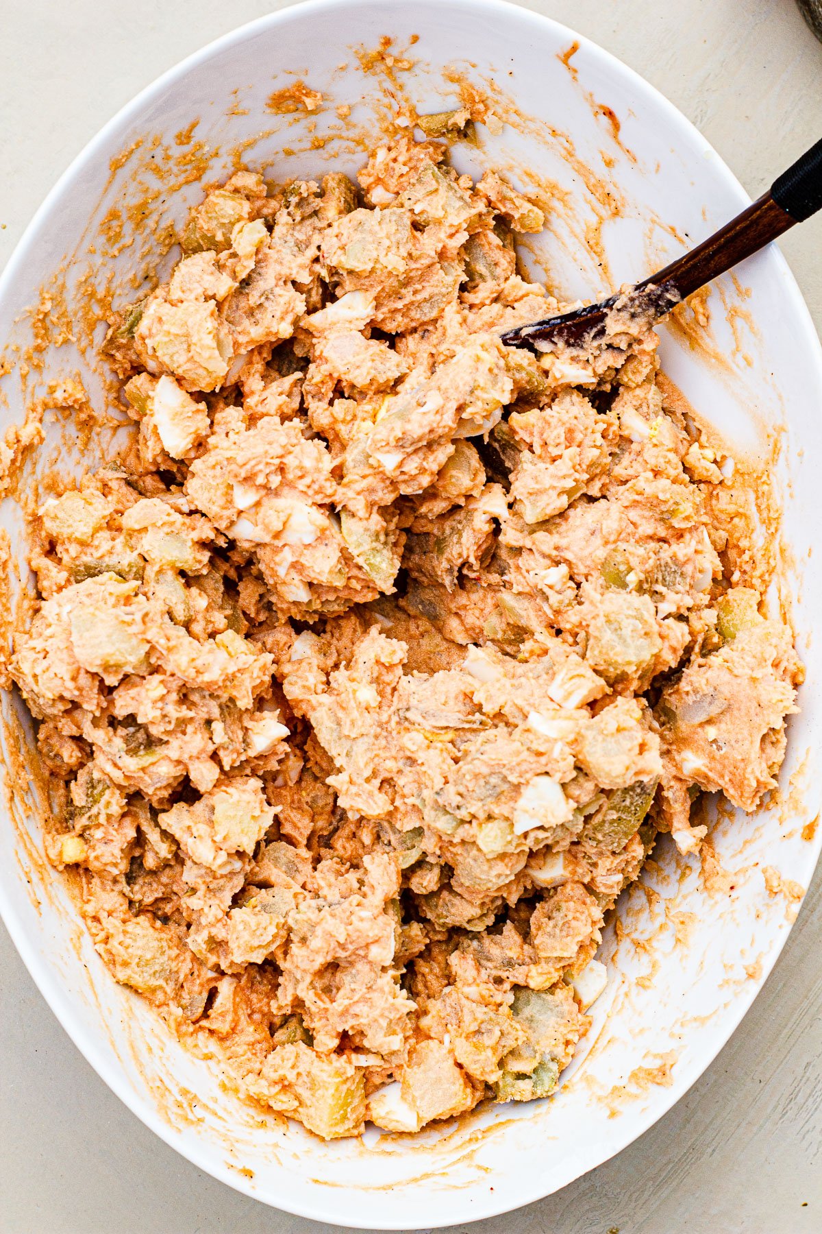 Potato salad all mixed in a bowl with a wooden spoon