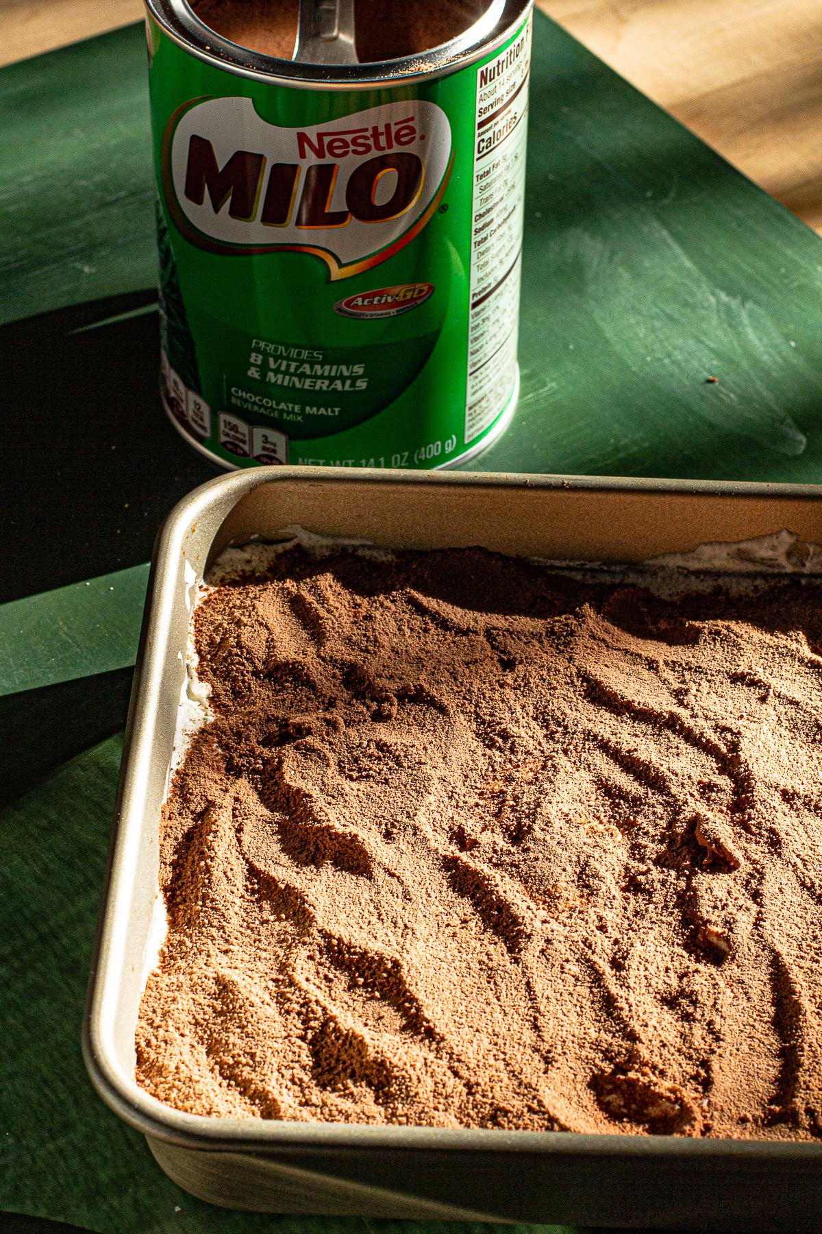 Milo covered Milo Tiramisu.  Milo can in the back on a green background.