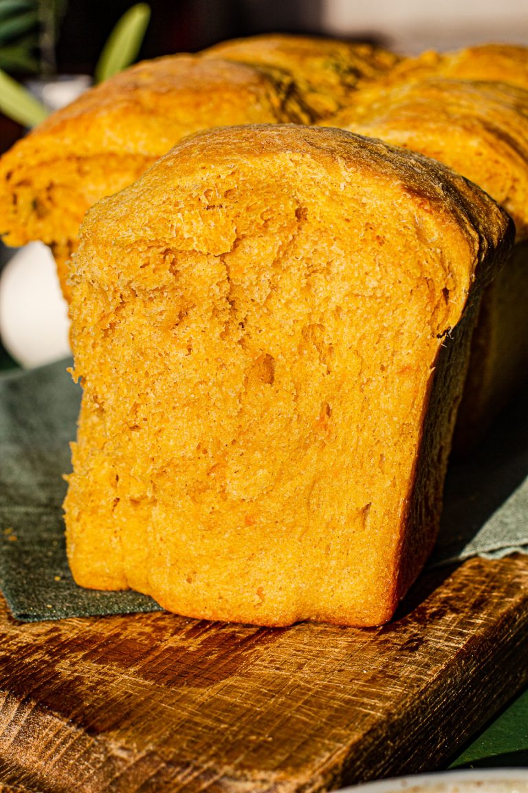 Slice of Kalabasa Bread on a wooden cutting board.