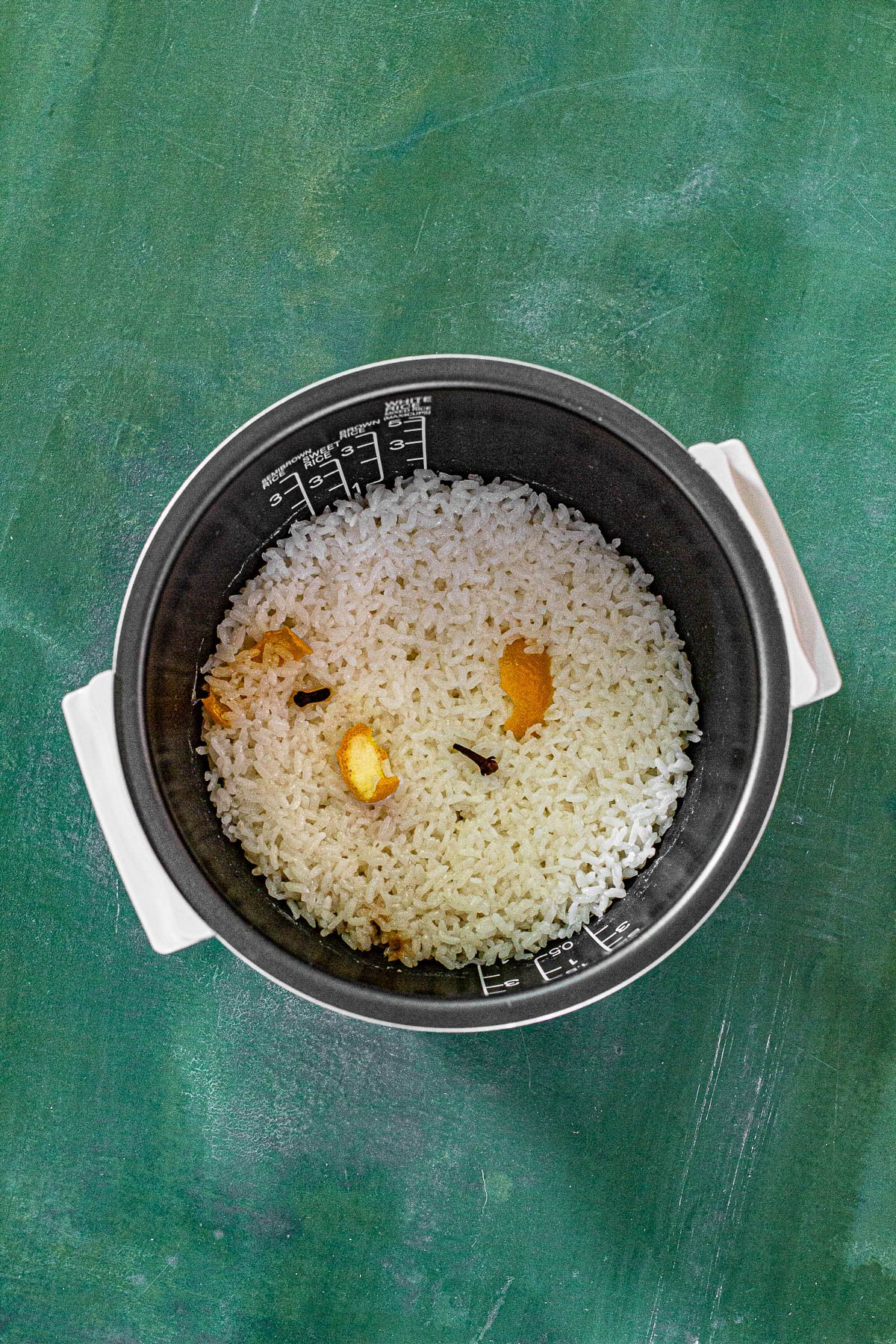 Sweet Sticky Rice in a rice cooker with orange peel and cloves.