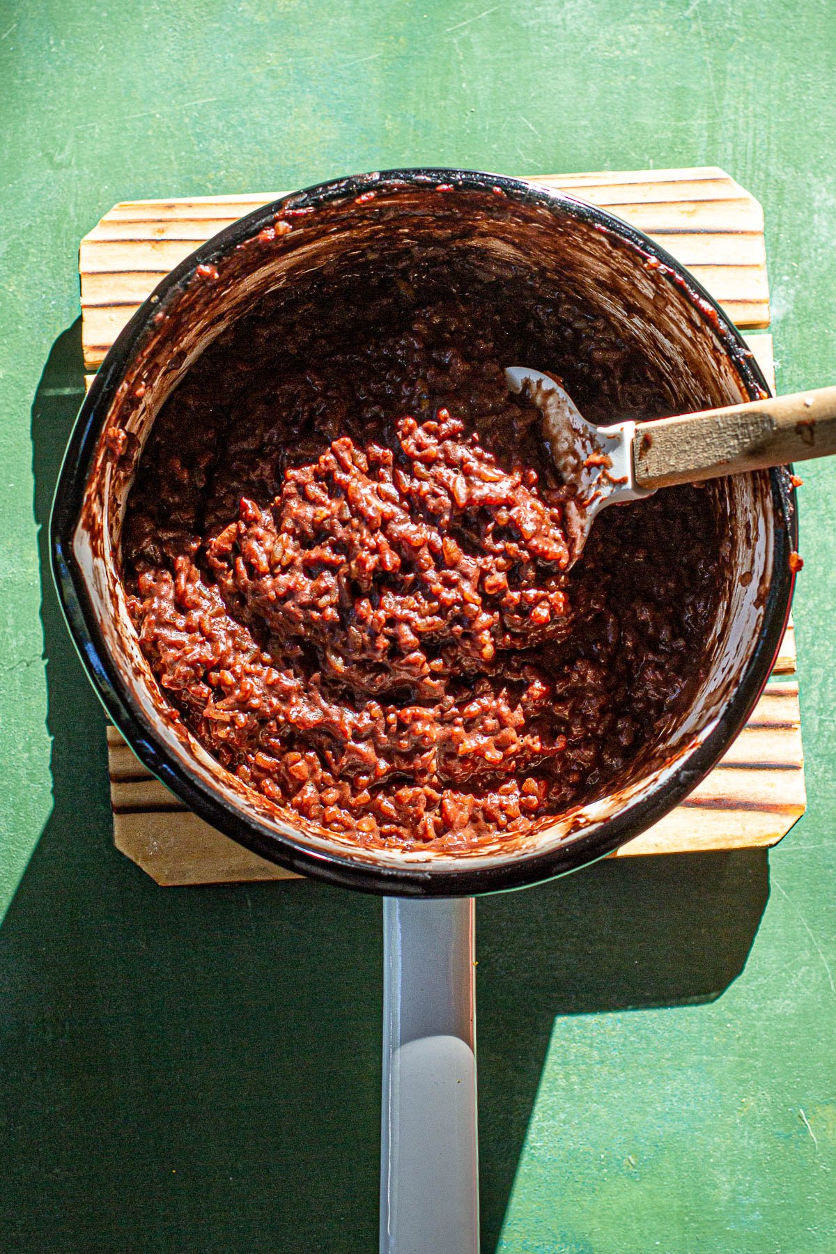 Cooked Biko in a sauce pan on a wooden board.