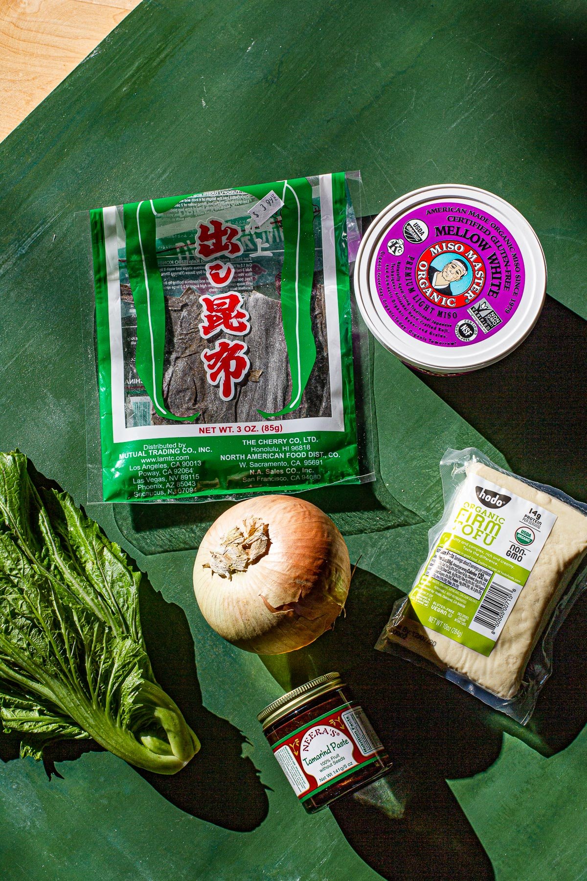 Kombu, Miso paste, mustasa, onion, tofu and tamarid paste on a green back drop. Ingreidents for Sinigang sa Miso at Mustasa.