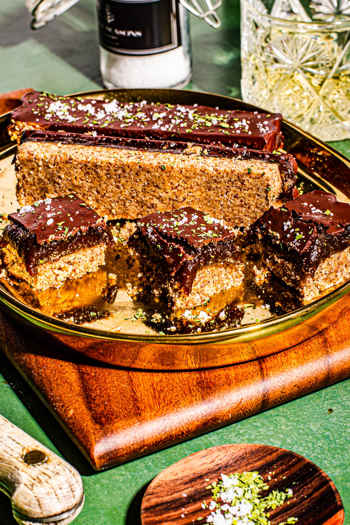 Millonariyo Bars (Filipino Style Millionaire Bars) on a gold plate on a small cutting board. All on a green background.