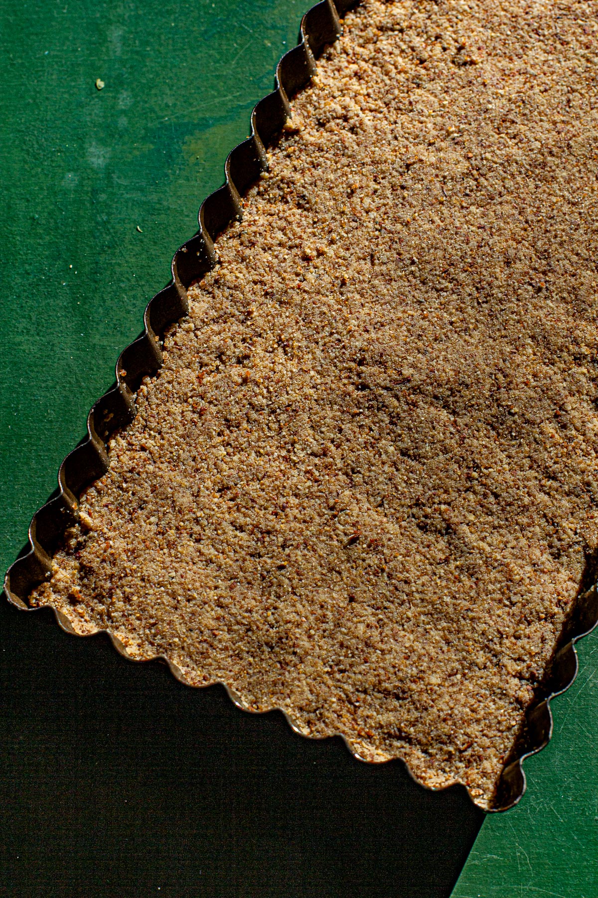 Polvoron pressed in a tart tin on a green backdrop.