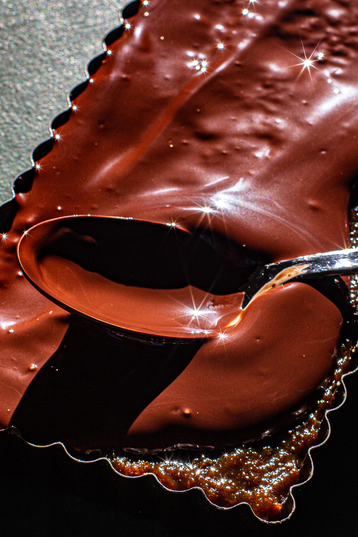 Melted Tableya spread on top of Matamis na bao with a spoon. Chocolate is sparkling.