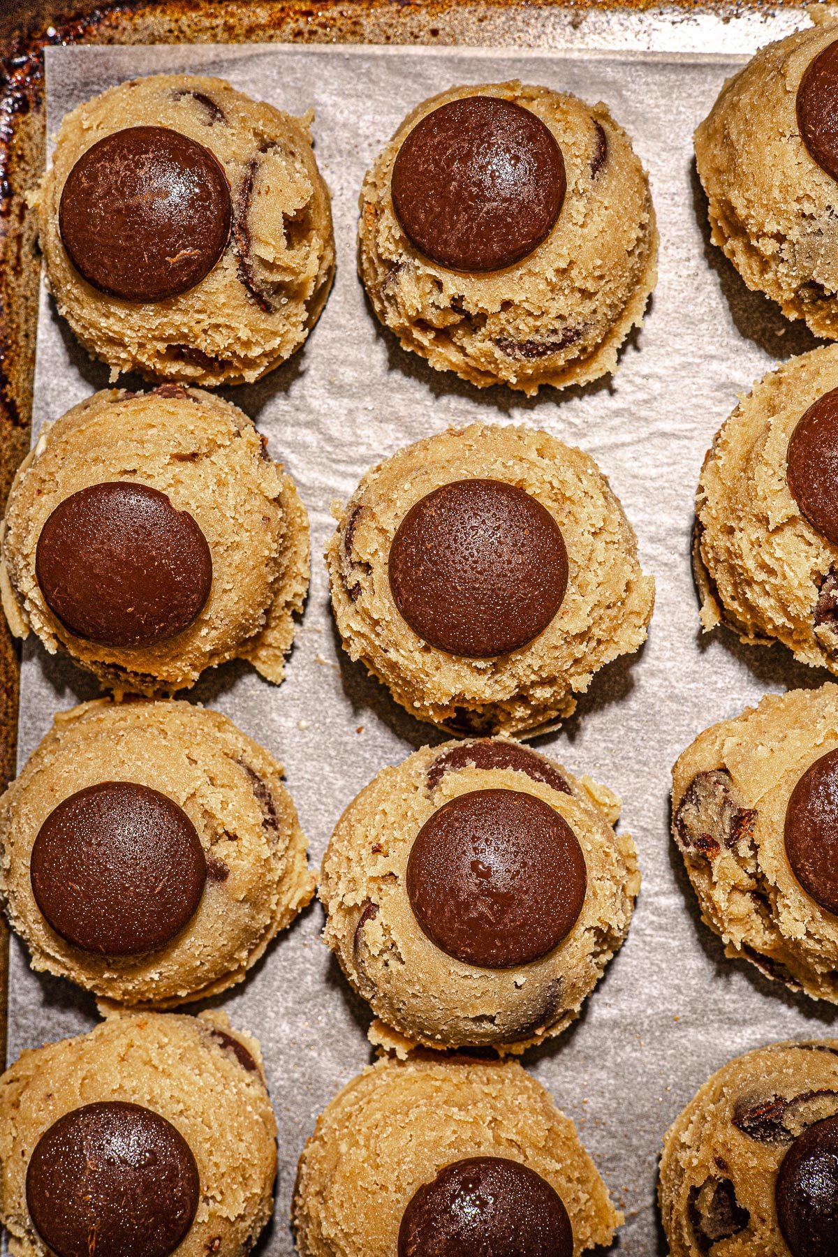 Raw cookie dough scopps on a baking tray.