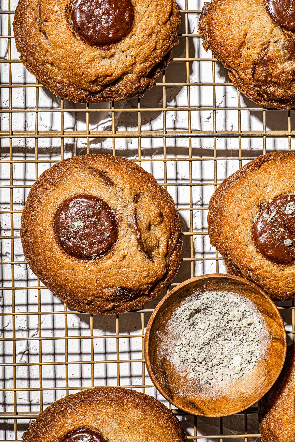 Chocolate Chunk Cookies cooling on a wire rack with salt in a wooden bowl.