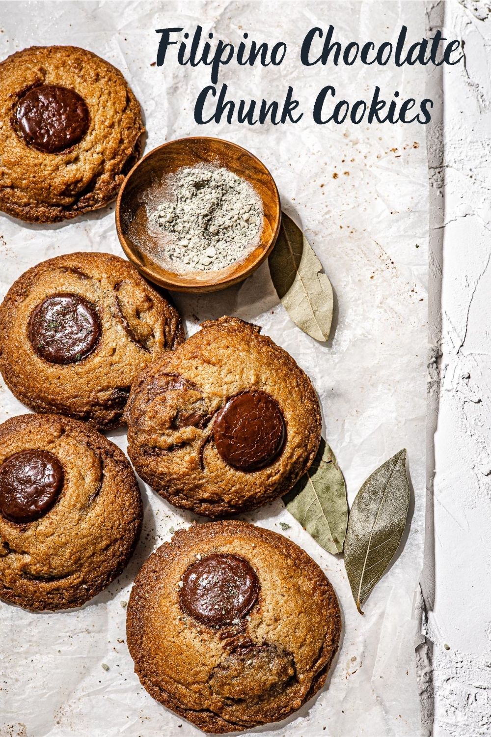 Chocolate Chunk Cookies on parchment paper with 3 dried bay leaves.
