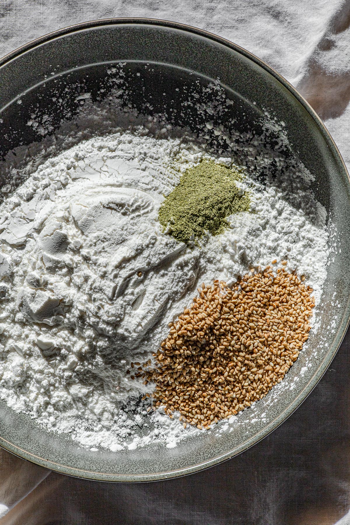 A green bowl with sweet glutinous rice flour, pandan powder and sesame seeds.