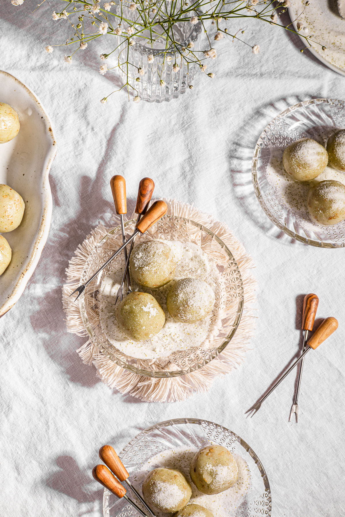 3 Balls of Mache (Buko Pandan Mochi Balls) on a glass plate with mini tongs on top of a macrame coaster.