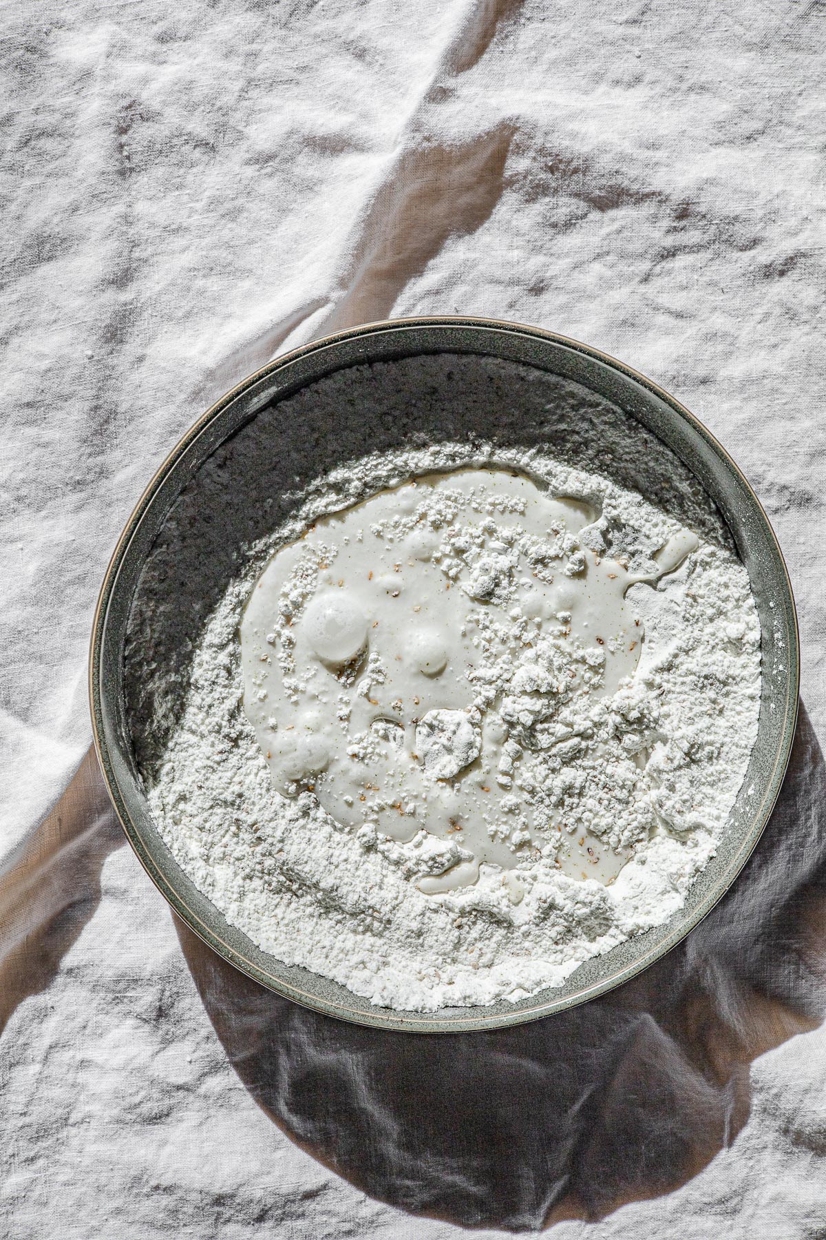 A bowl of glutinous rice flour with coconut milk on a white linen table cloth.