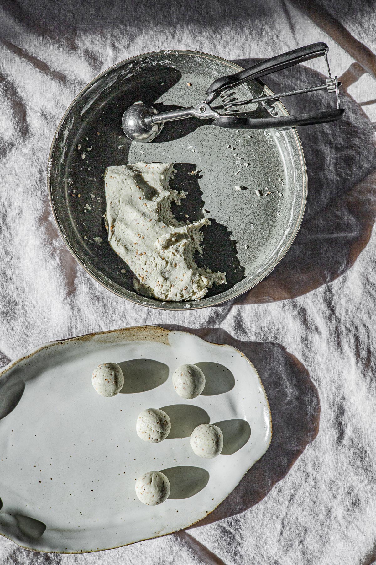 Mache dough in a green bowl with an ice cream scooper.  A platter with rolled mache balls.