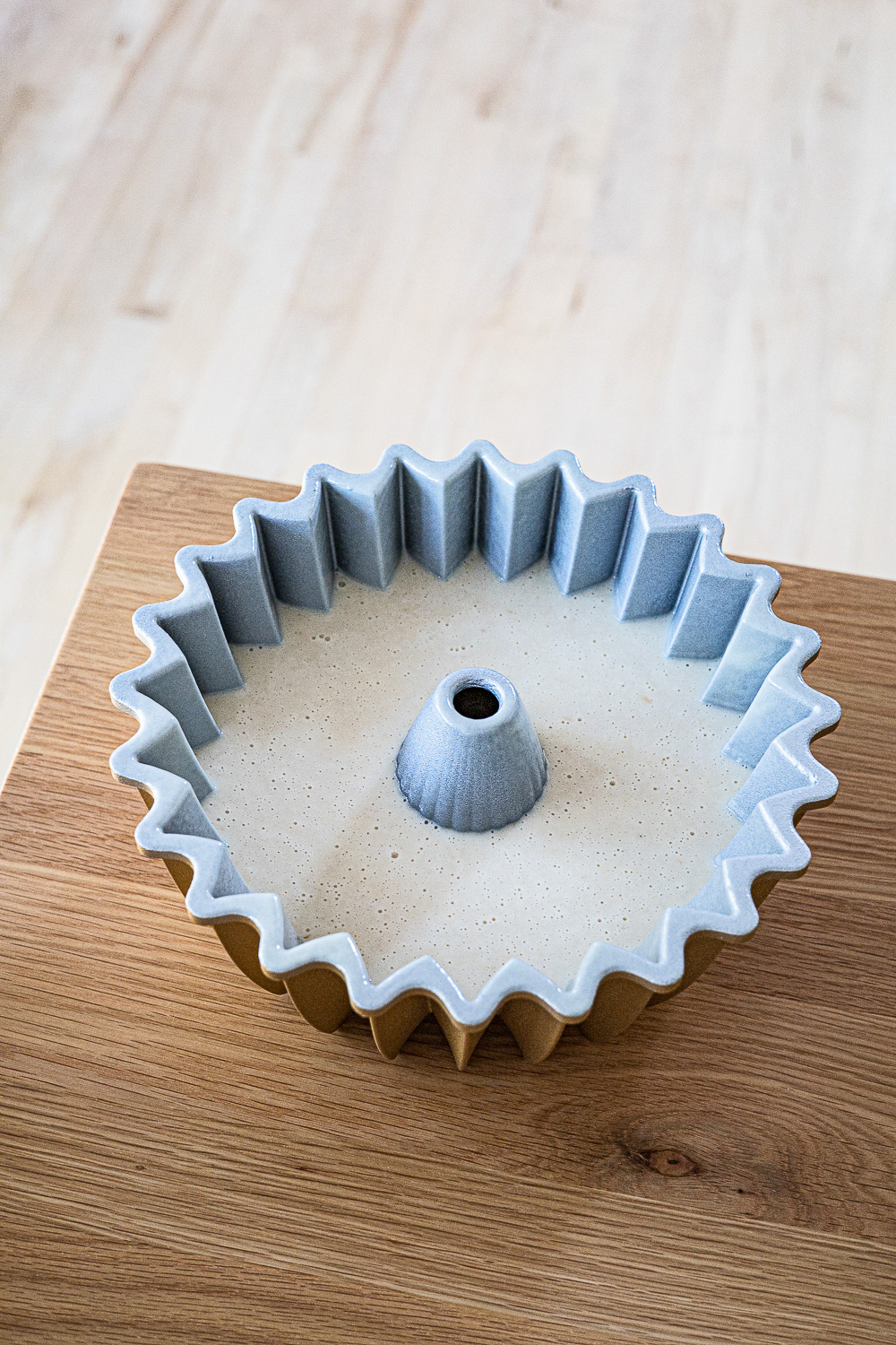 Lychee cake batter in a bundt pan on a wooden table.