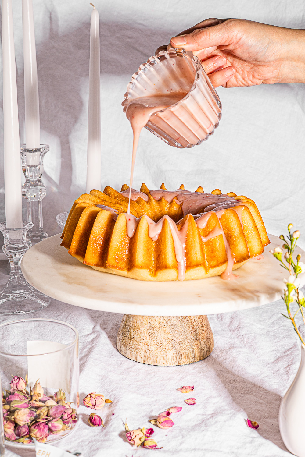 Ispahan Cake being drizzled with raspberry rose icing.
