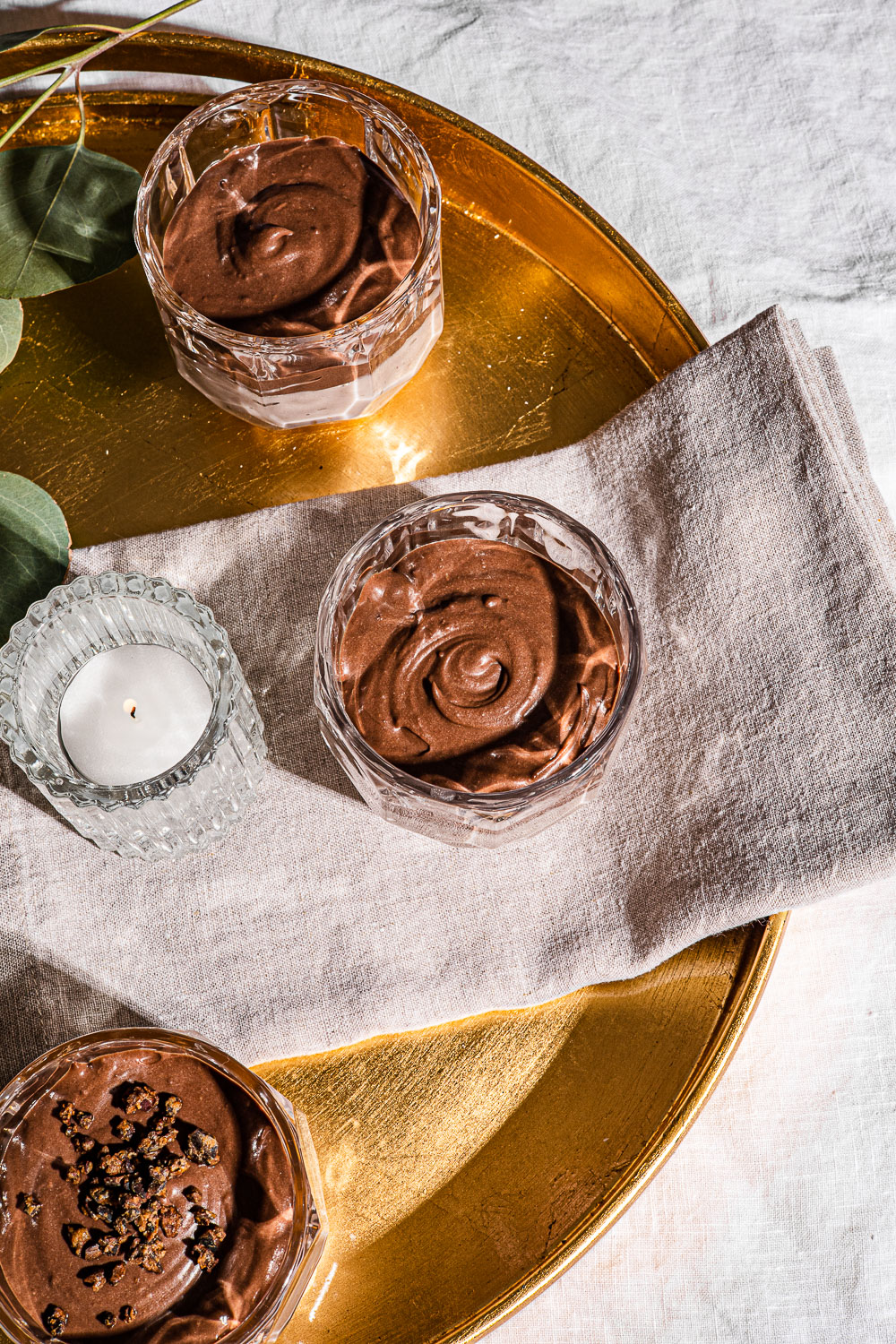 Chocolate and Strawberry Pudding in a glass on a round gold tray.
