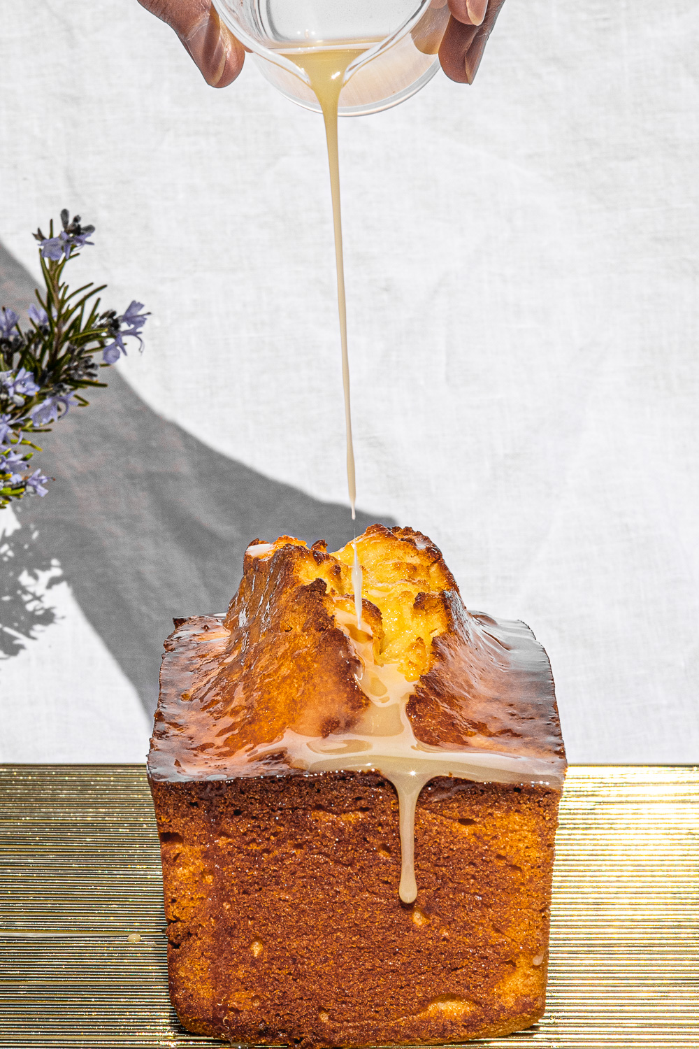 Glaze being poured on Kalamansi Pound Cake on a gold wire rack.