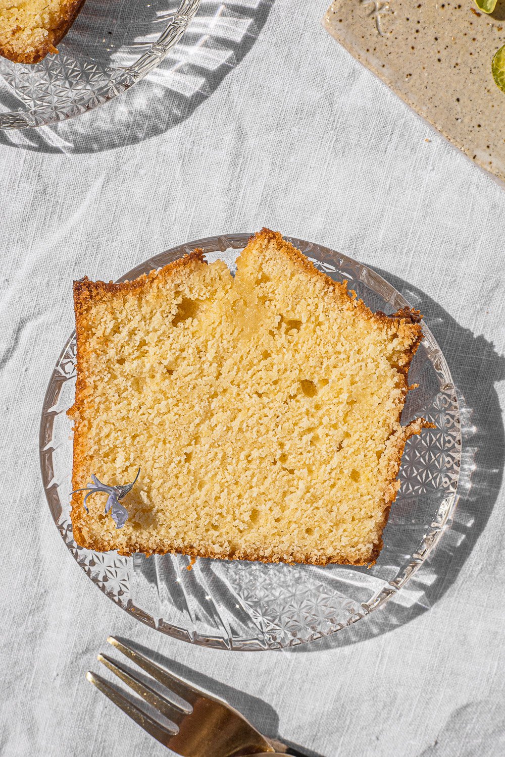 Slice of pound cake on a glass plate with a fork on the side.