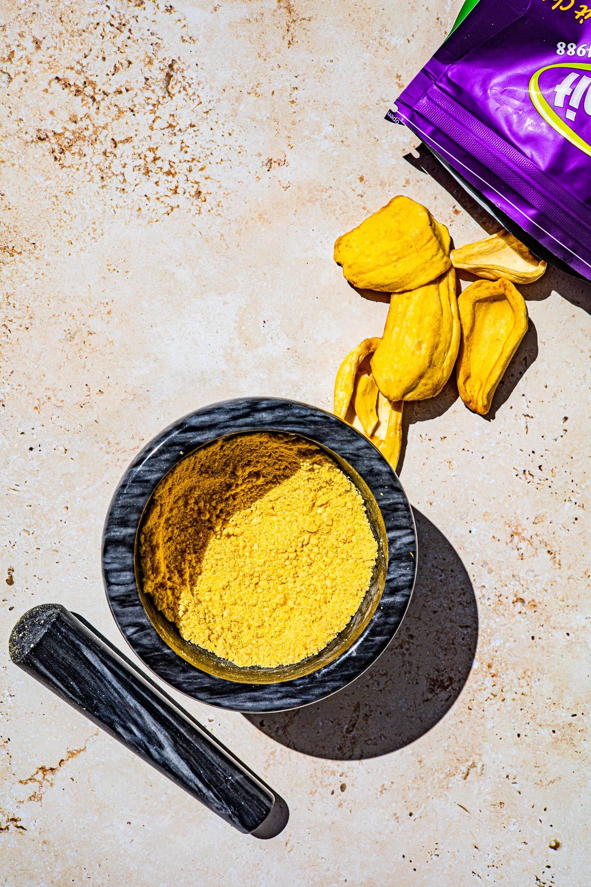 Bag of dehydrated langka with langka chips coming out.  Langka powder in a marble bowl.