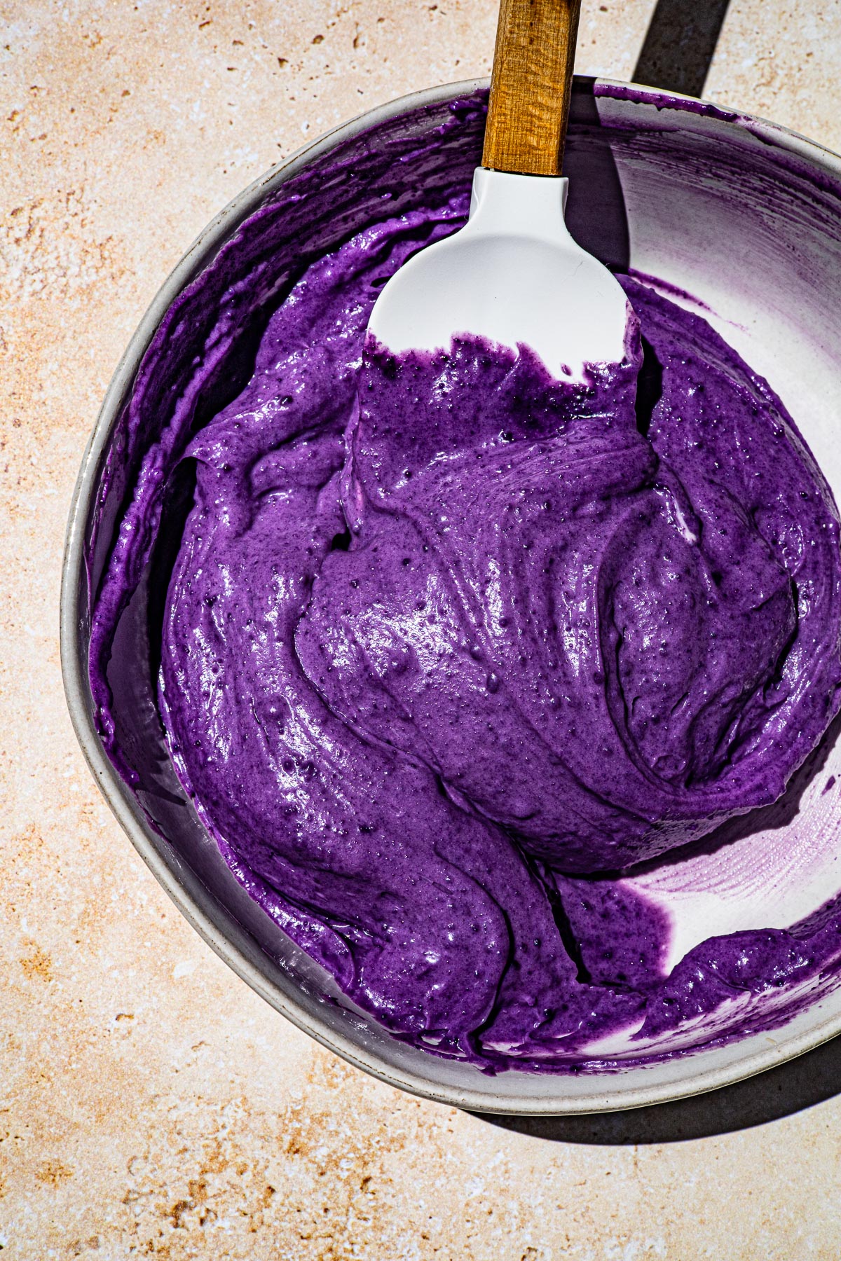 Ube cookie butter and mascarpone mixed together in a bowl to make frosting.