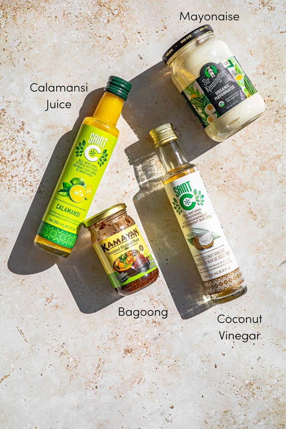 Ingredients for dressing.  Jar of mayonnaise, bottle of calamasi, jar of bagoon, bottle of coconut vinegar.