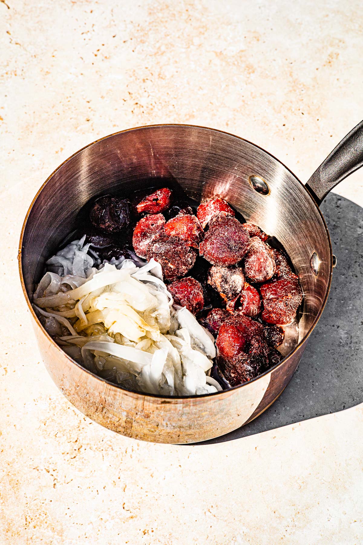 Frozen cherries, macapuno strings and vanilla in a sauce pan.