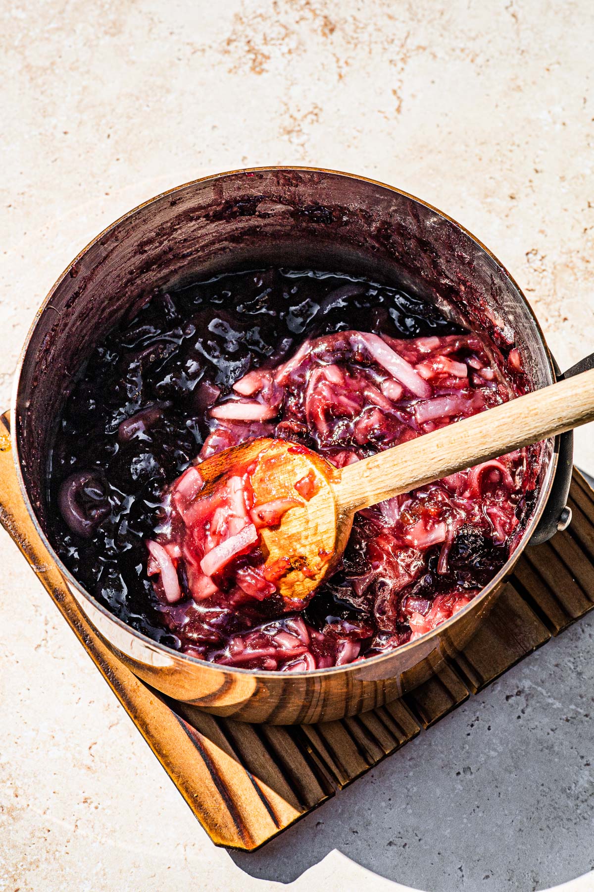 Finished cherry macapuno filling in a sauce pan with a wooden spoon mixing.