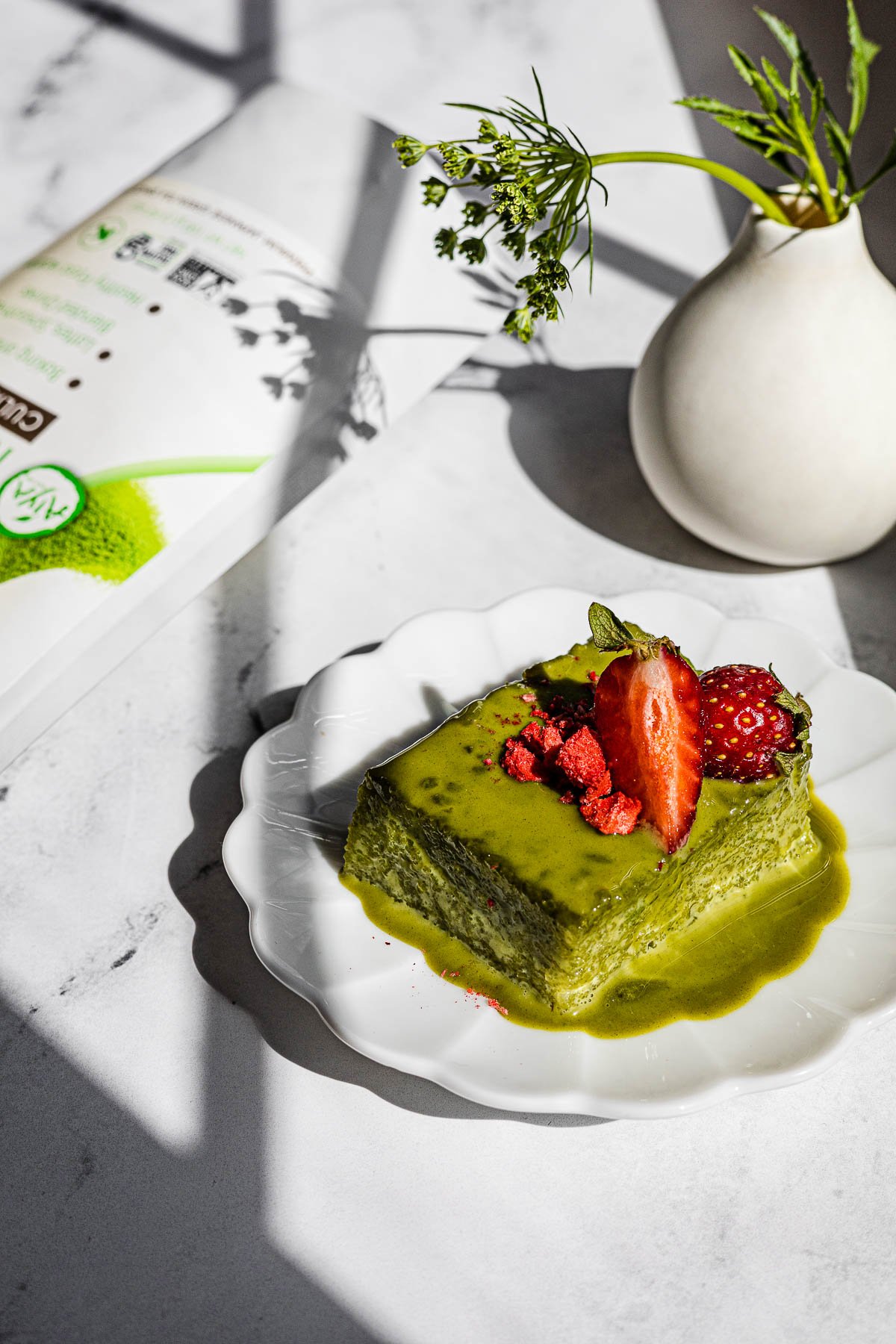 Slice of Biko with strawberries.  Matcha bag in the background.