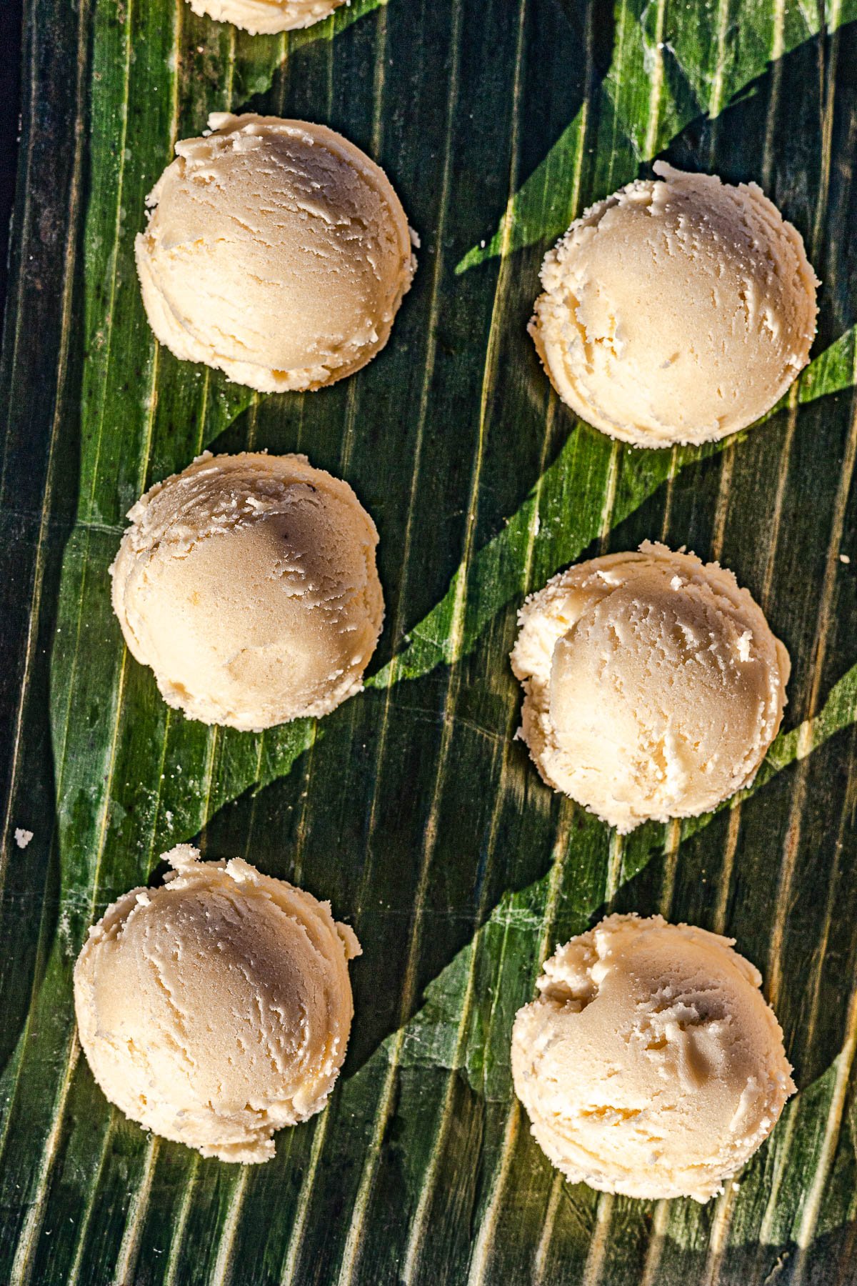 Scoops of dough on a banana leaf.