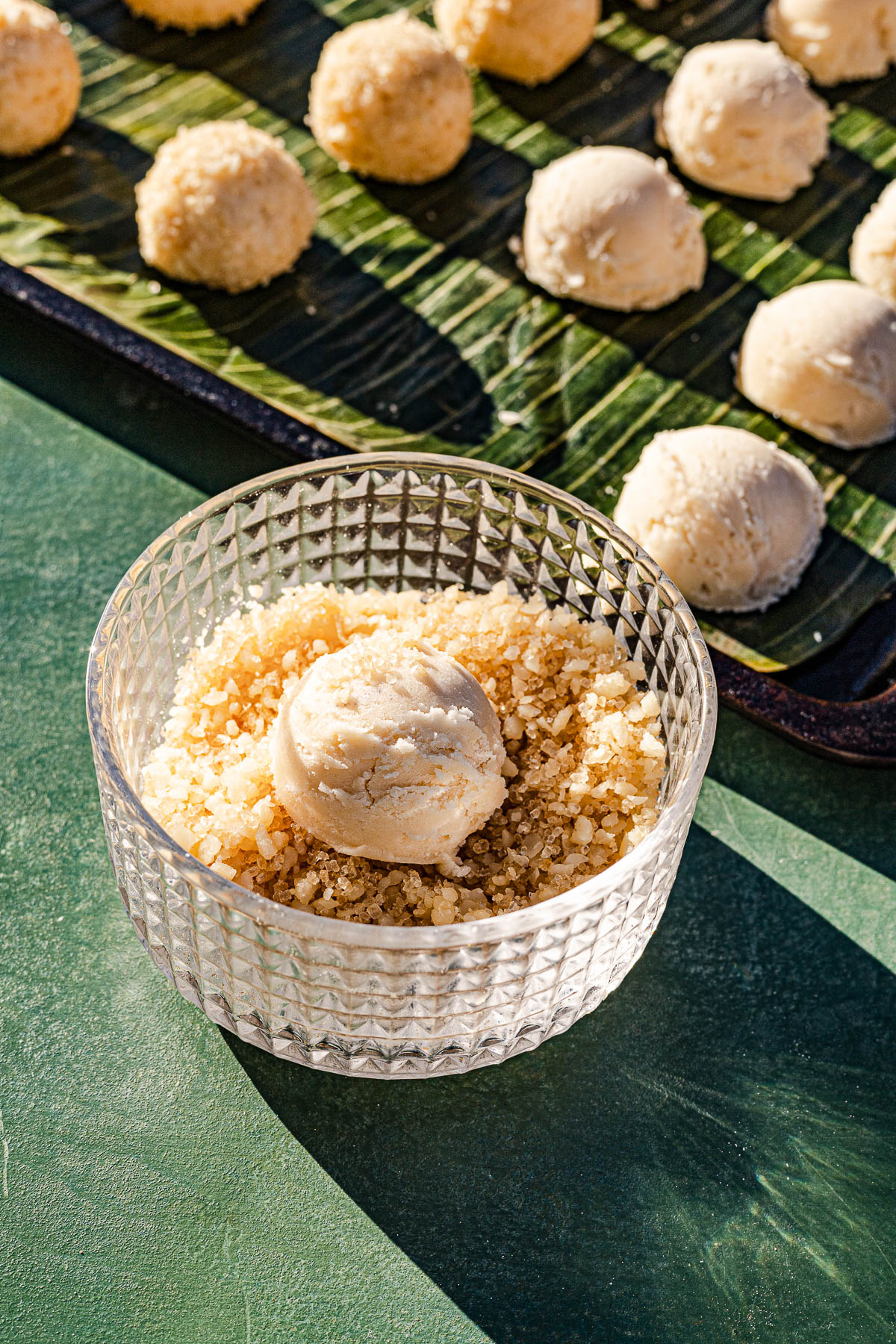 Dough in a glass bowl of parmesan and sugar.