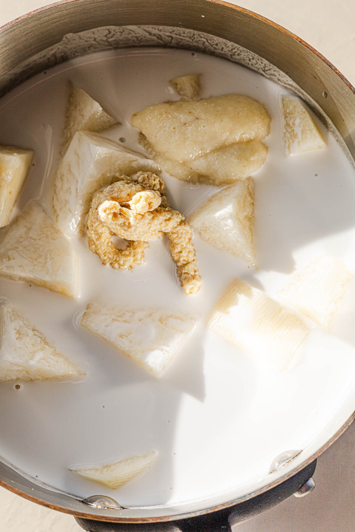 Cubed potatoes in a sauce pan with coconut milk, ginger and garlic.