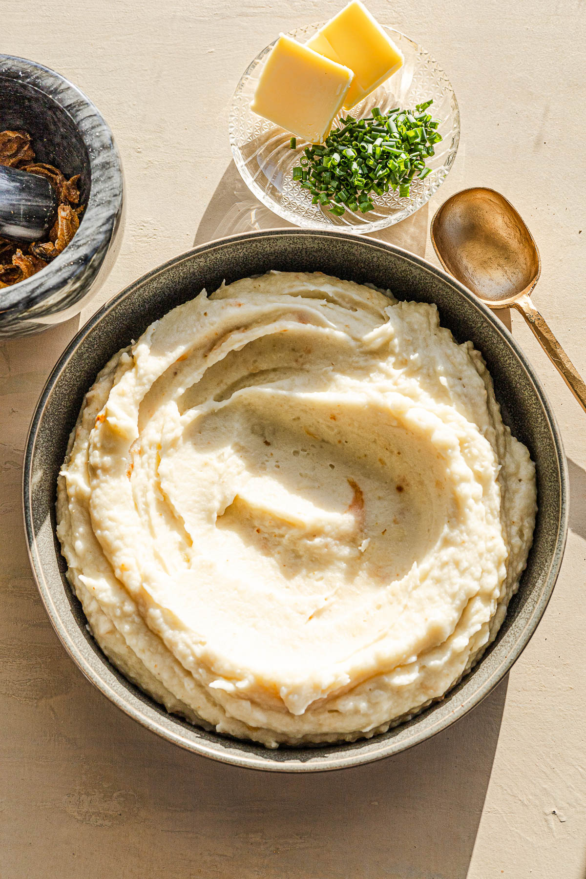 Ginataang Mashed Potato in a serving dish with the dilis and chives on the side.
