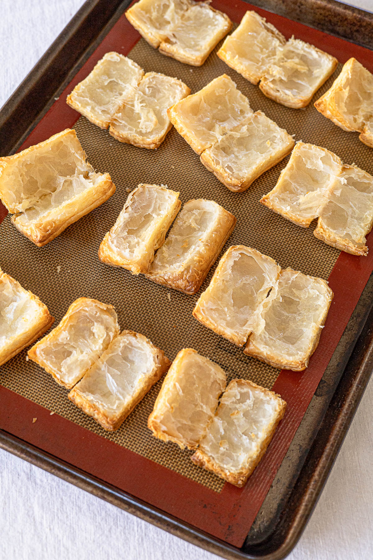 Napoleones pastry split in half on a baking sheet.