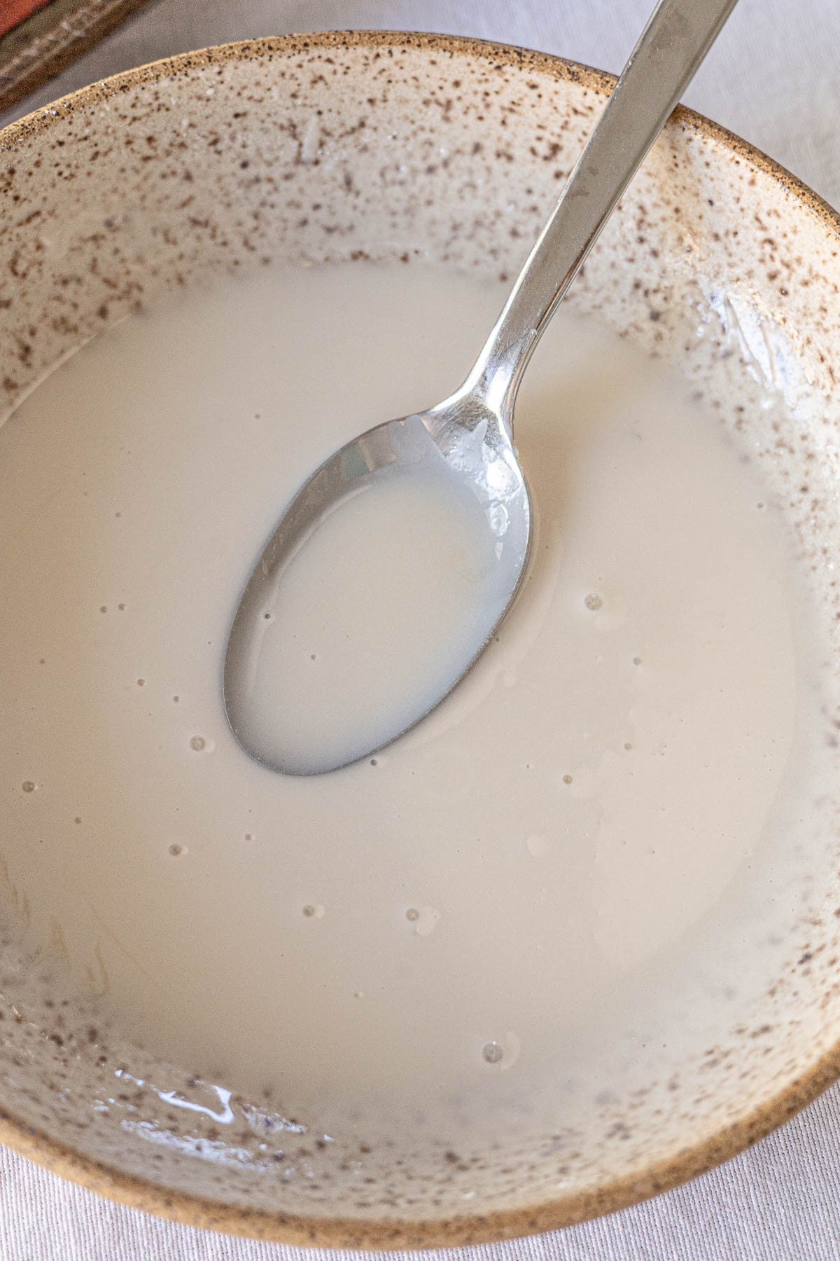 Powdered sugar glaze in a bowl with a spoon in the bowl