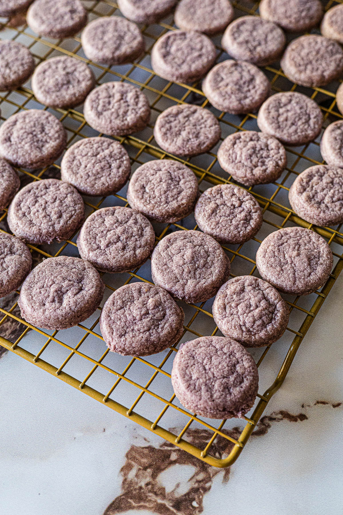 Ube Tea Cookies cooling on a gold wire rack.