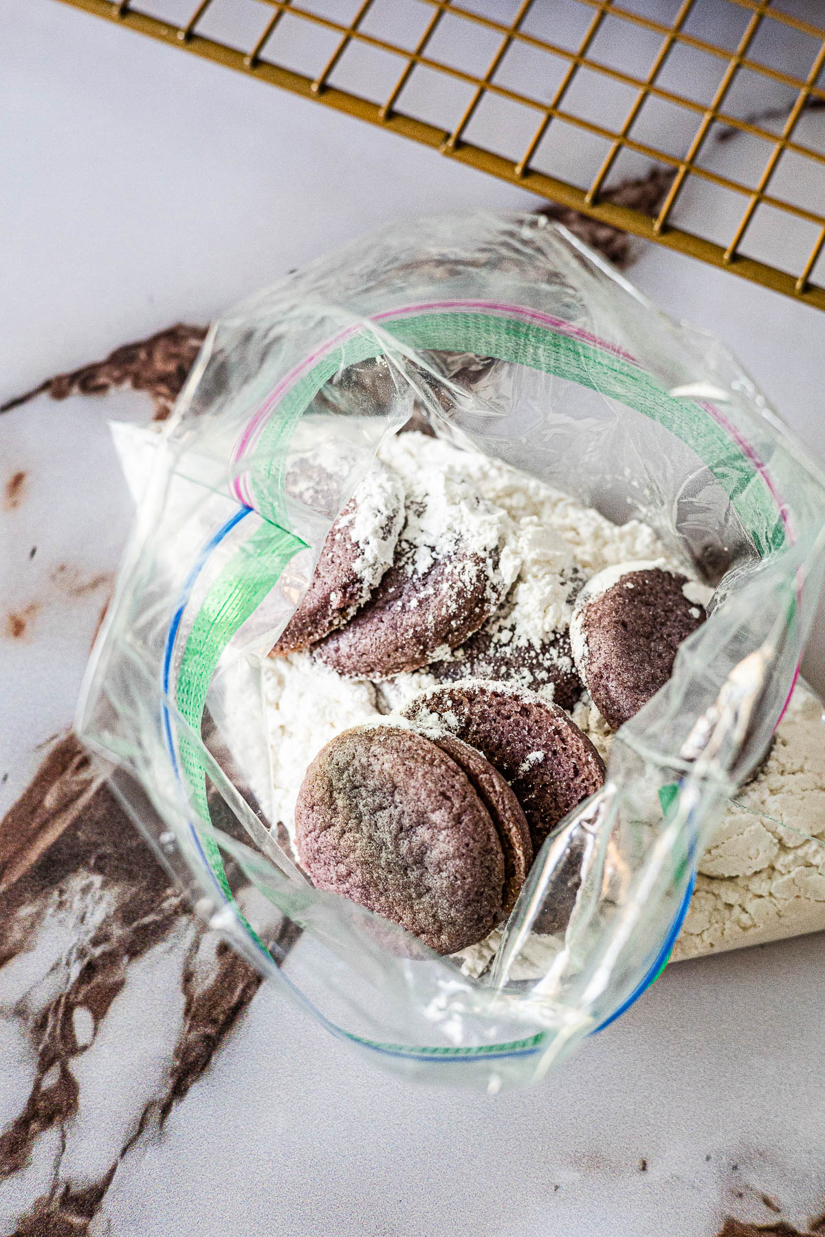 Cookies in a ziplock bag with powdered sugar and ube powder.