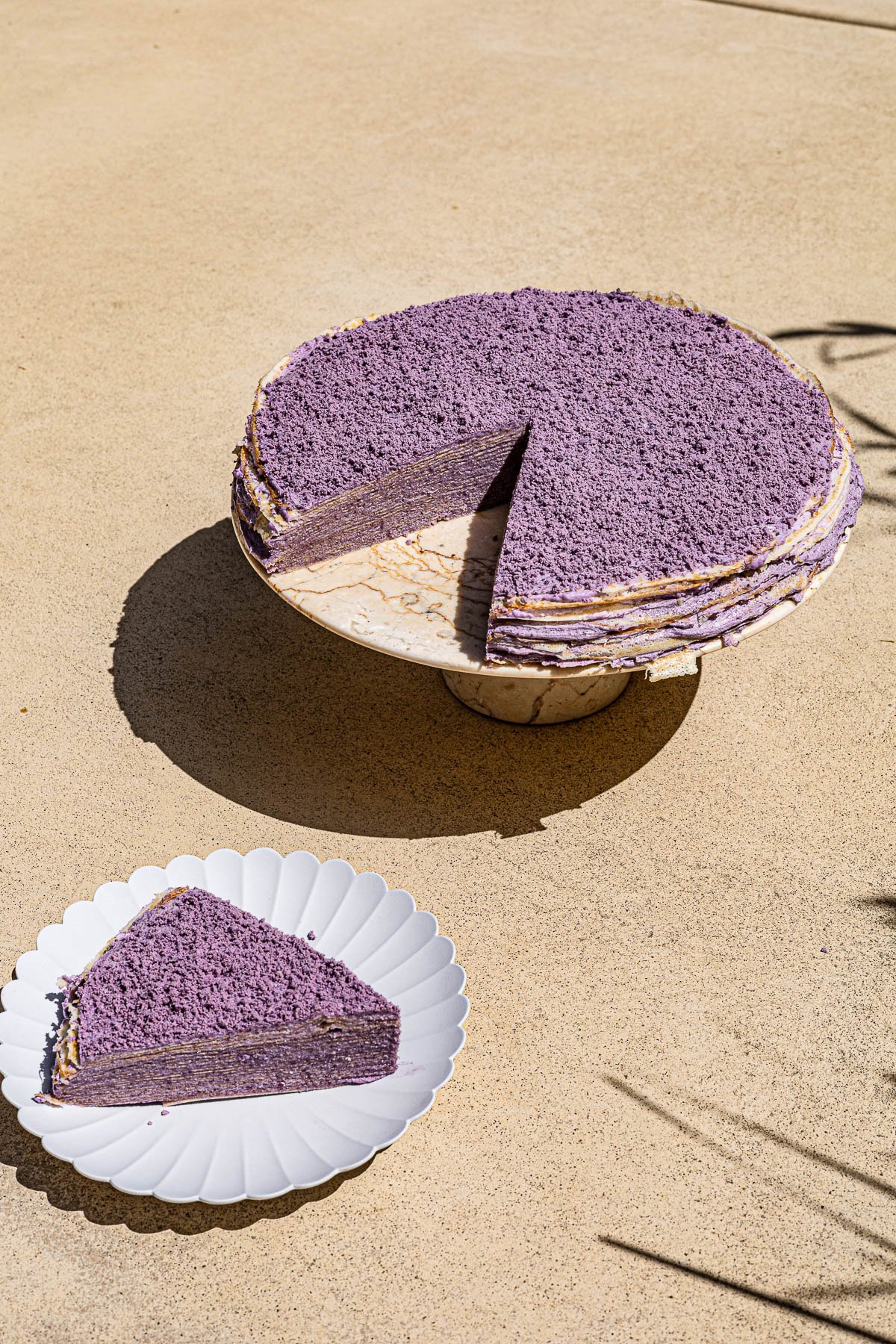 Ube Crepe Cake on a marble cake stand.