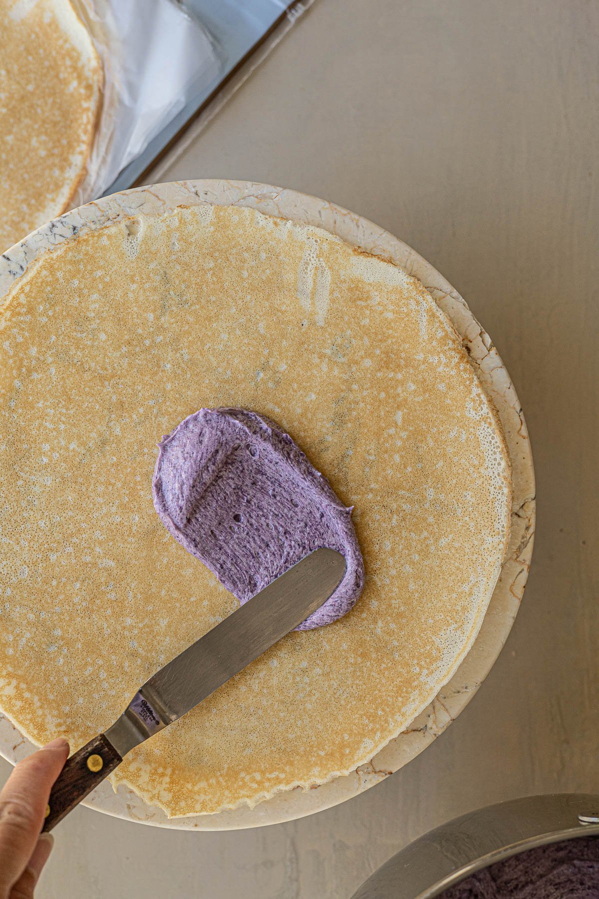 spreading ube cream over crepe